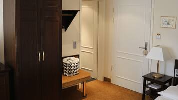 A hotel room with a large wardrobe, a bedside table with a lamp, and a carpeted floor.