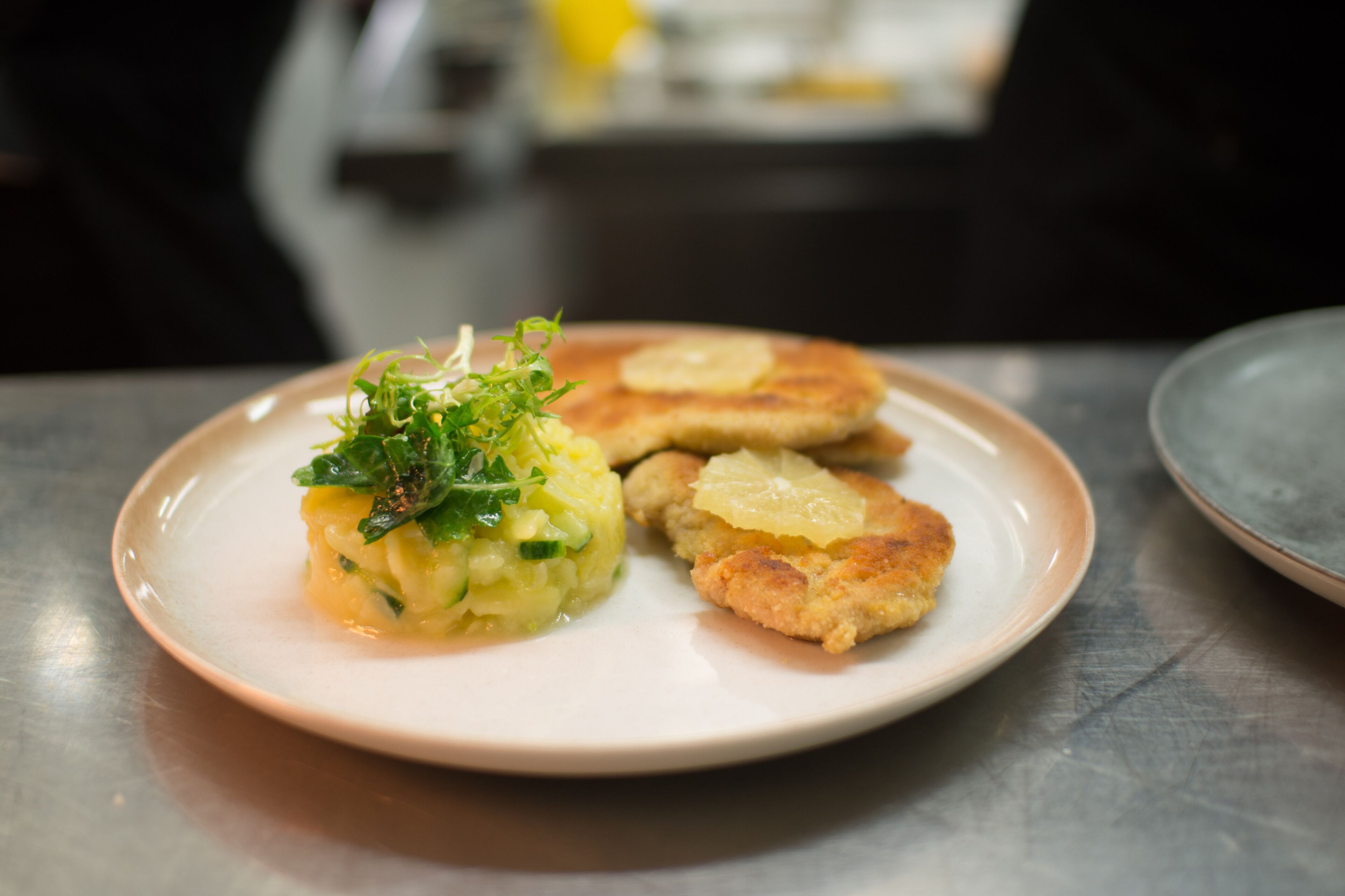 Une assiette contenant divers aliments, notamment une boulette, un morceau de viande pané et une garniture.