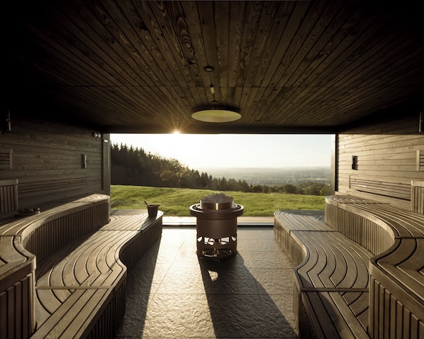 Uma sauna com vista para uma paisagem verde e teto de madeira.