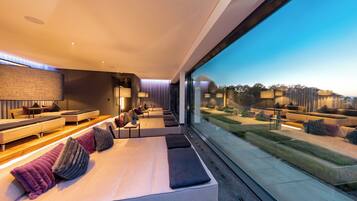 Un dormitorio moderno con una cama grande, zona de estar y vistas al exterior.