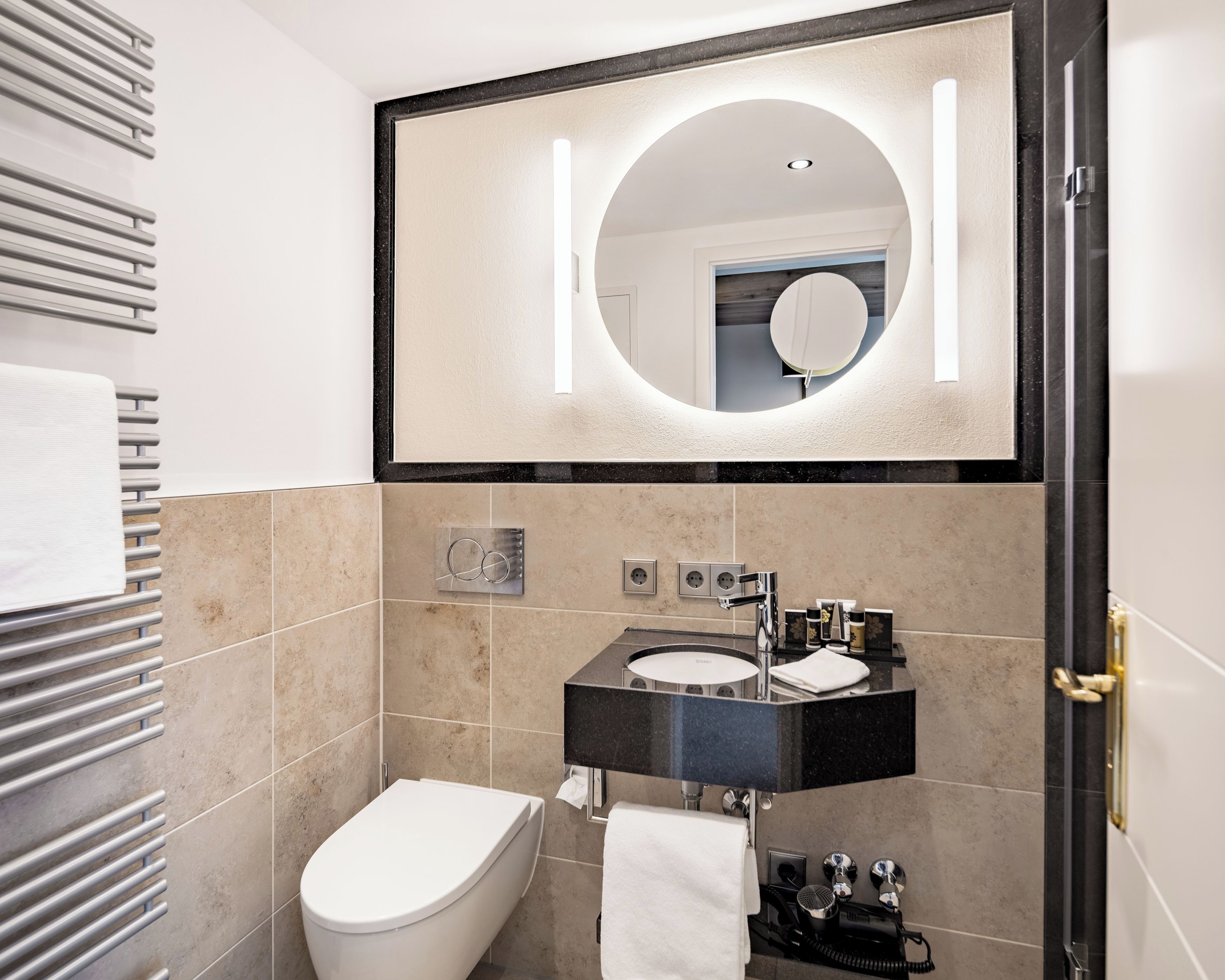 A modern bathroom with a toilet, sink, and mirror.