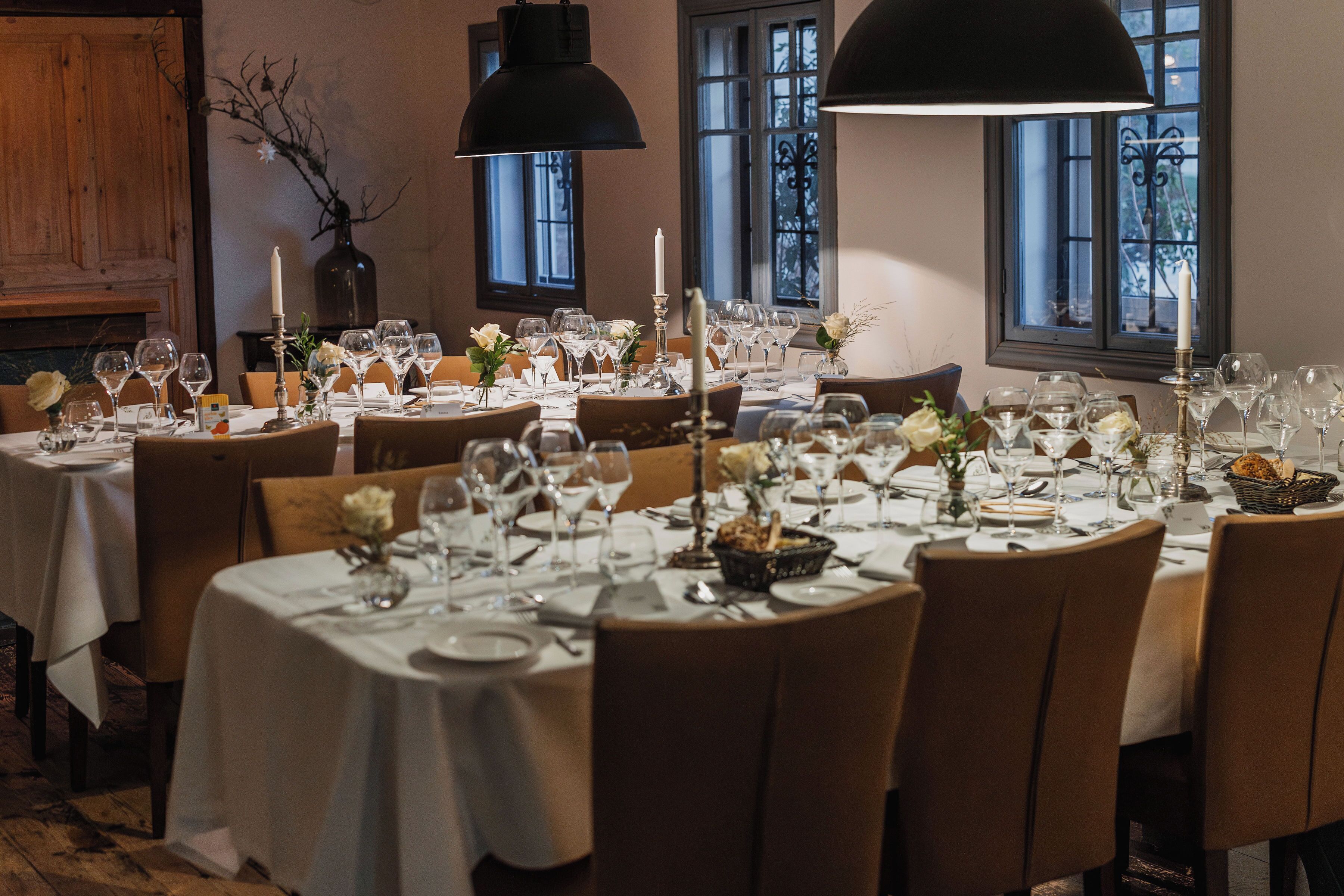 En restaurant med runde borde dækket til spisning, hvide dugge, vinglas og stearinlys.