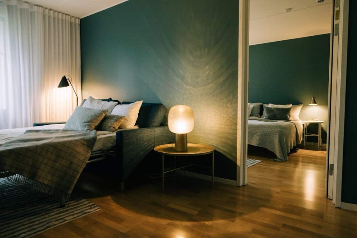 A modern bedroom with a large bed, a bedside table with a lamp, and a mirror.