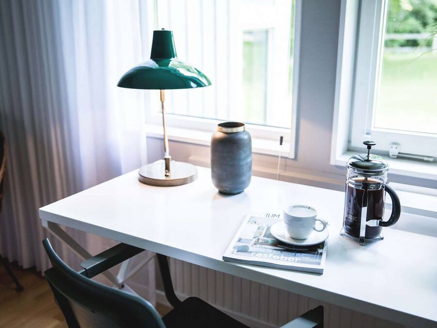 A table with a coffee maker, a cup, a vase, and a lamp.