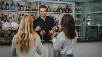 Een bar met flessenkast vol drank, een toog en iemand die drankjes uitserveert.