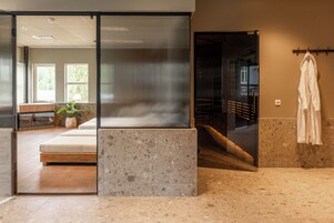 Un interior moderno con un separador de vidrio, un banco y una planta.