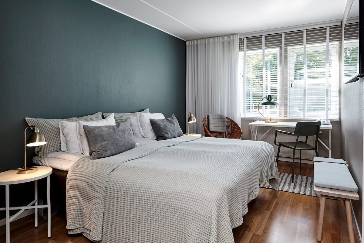A modern bedroom with a bed, bedside tables, a desk, and a chair.
