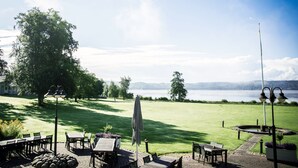 A patio with tables and chairs overlooking a lake. - Aspenäs Herrgård (Lerum)