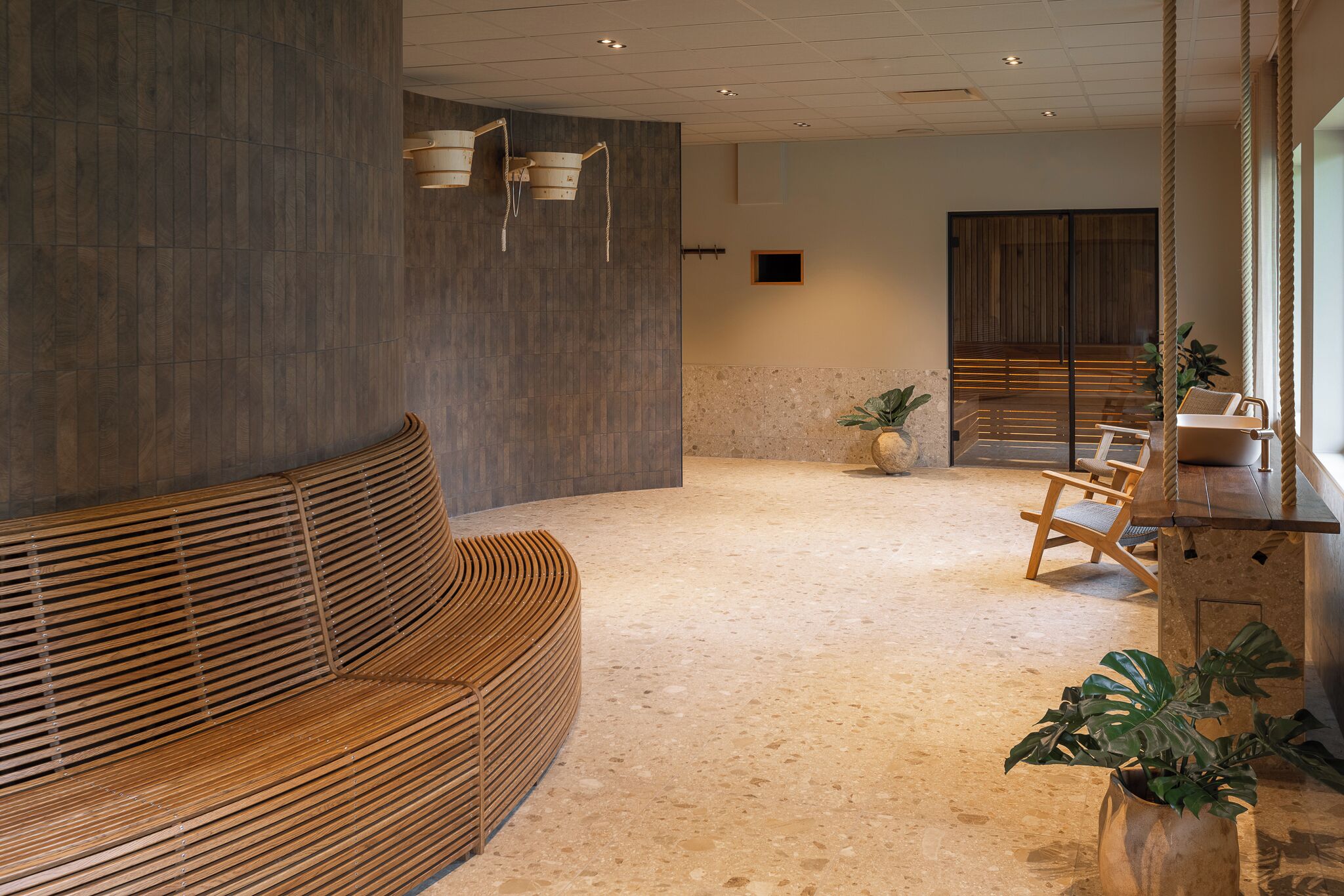 Un interior moderno con un banco de madera, suelo de piedra y una recepción de madera.
