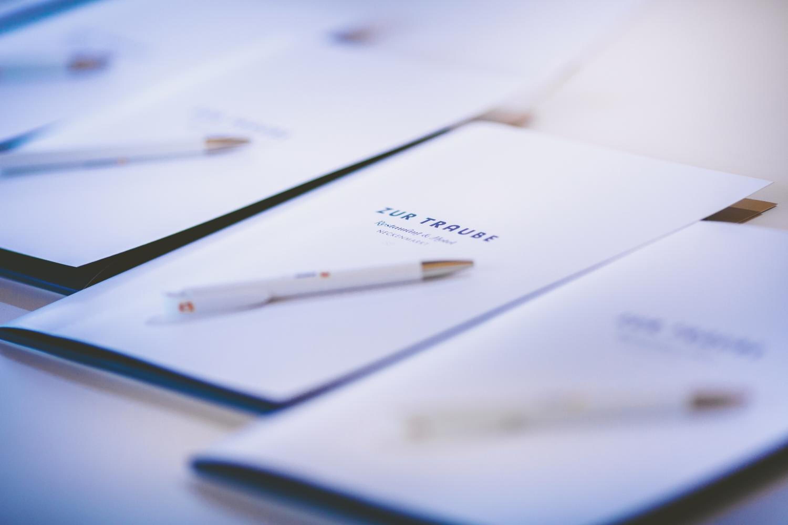 A brochure with the text "ZUR TRAUBE" and a pen on it.
