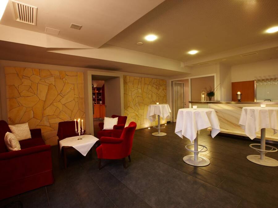 Un moderno vestíbulo de hotel con asientos rojos, mesas blancas y una zona de recepción.