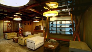 A traditional Japanese-style room with tatami flooring, low wooden furniture, and a display of bonsai trees. - Hotel Matsubara (Campos do Jordão)