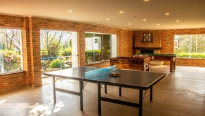 A spacious room with a ping pong table, a foosball table, and a fireplace. - Hotel Matsubara (Campos do Jordão)