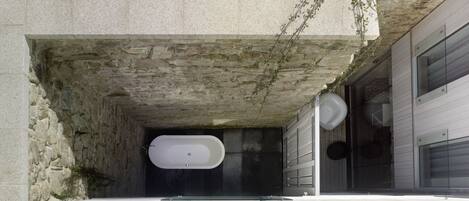 A modern bathroom with a freestanding bathtub, stone walls, and a minimalist design.