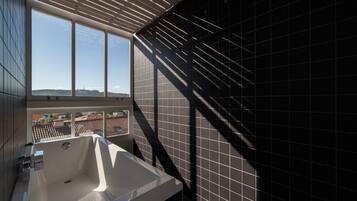 Une salle de bain moderne avec une grande baignoire, une fenêtre et une vue sur le paysage urbain.