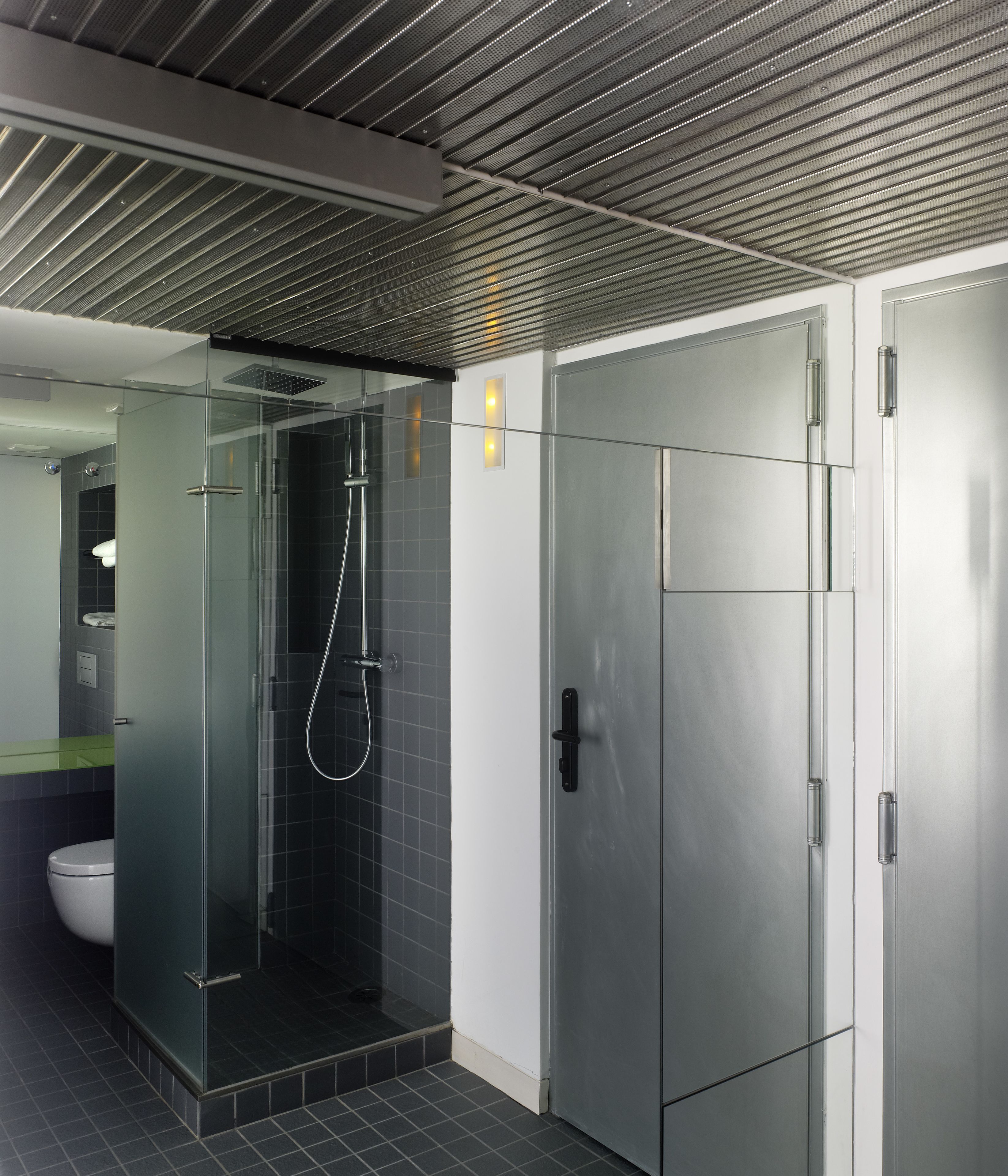 A modern bathroom with a glass-enclosed shower, a toilet, and a sink.