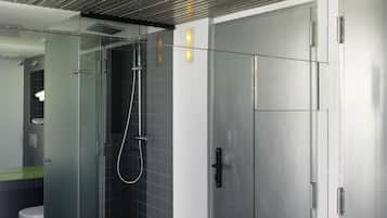 A modern bathroom with a glass-enclosed shower, a toilet, and a sink.