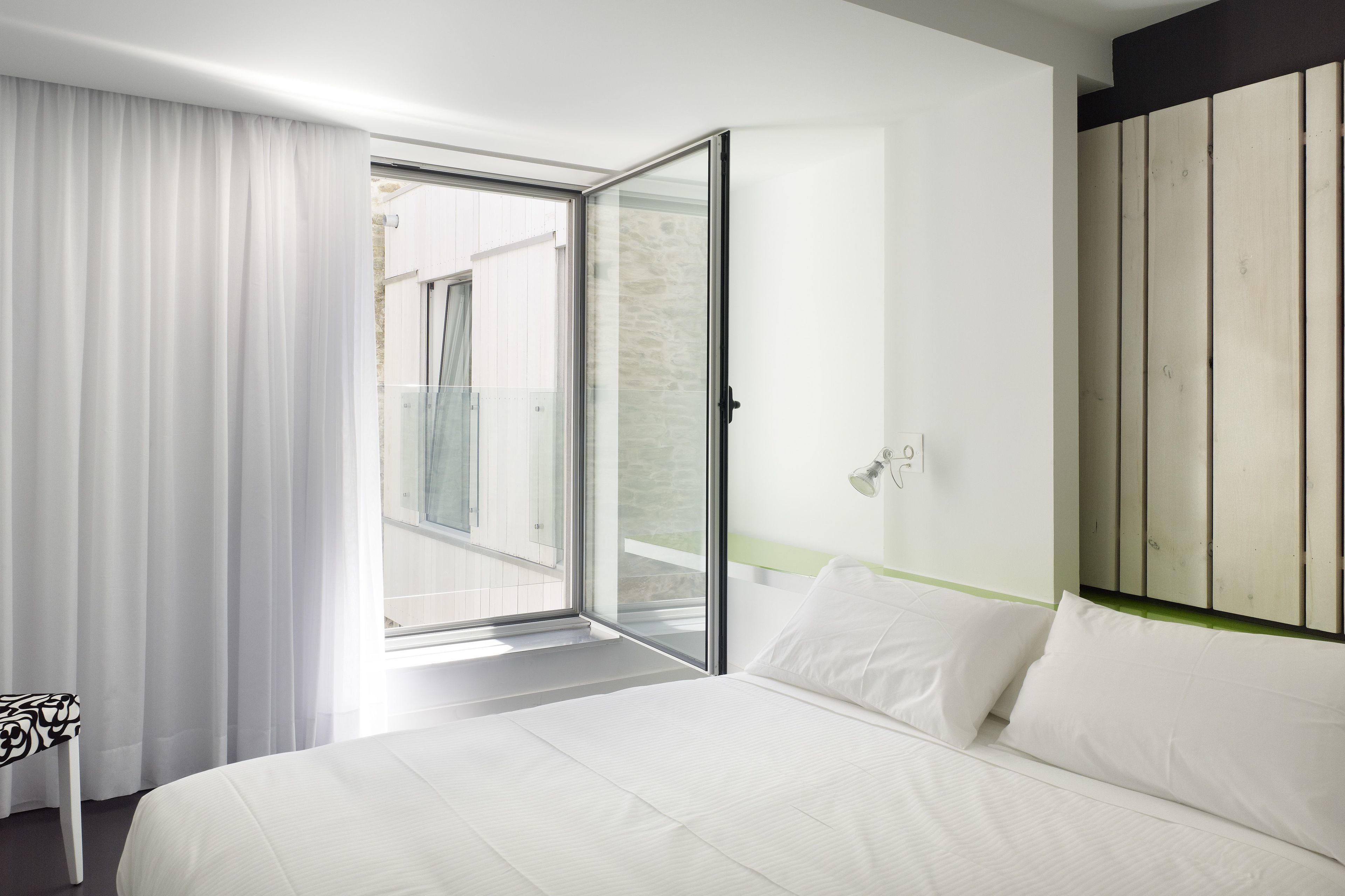 Habitación de hotel moderna con una cama grande, una puerta corrediza de vidrio a un balcón y un diseño minimalista.