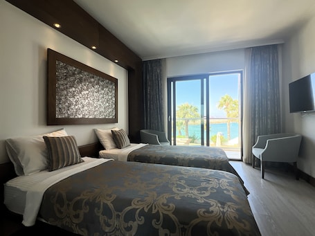A hotel room with two beds, a large artwork on the wall, a balcony with a view, and a TV mounted on the wall.