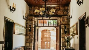 A hallway with a wooden ceiling, stone walls, and a patterned rug leading to a wooden door. - The Ninova (Antalya)