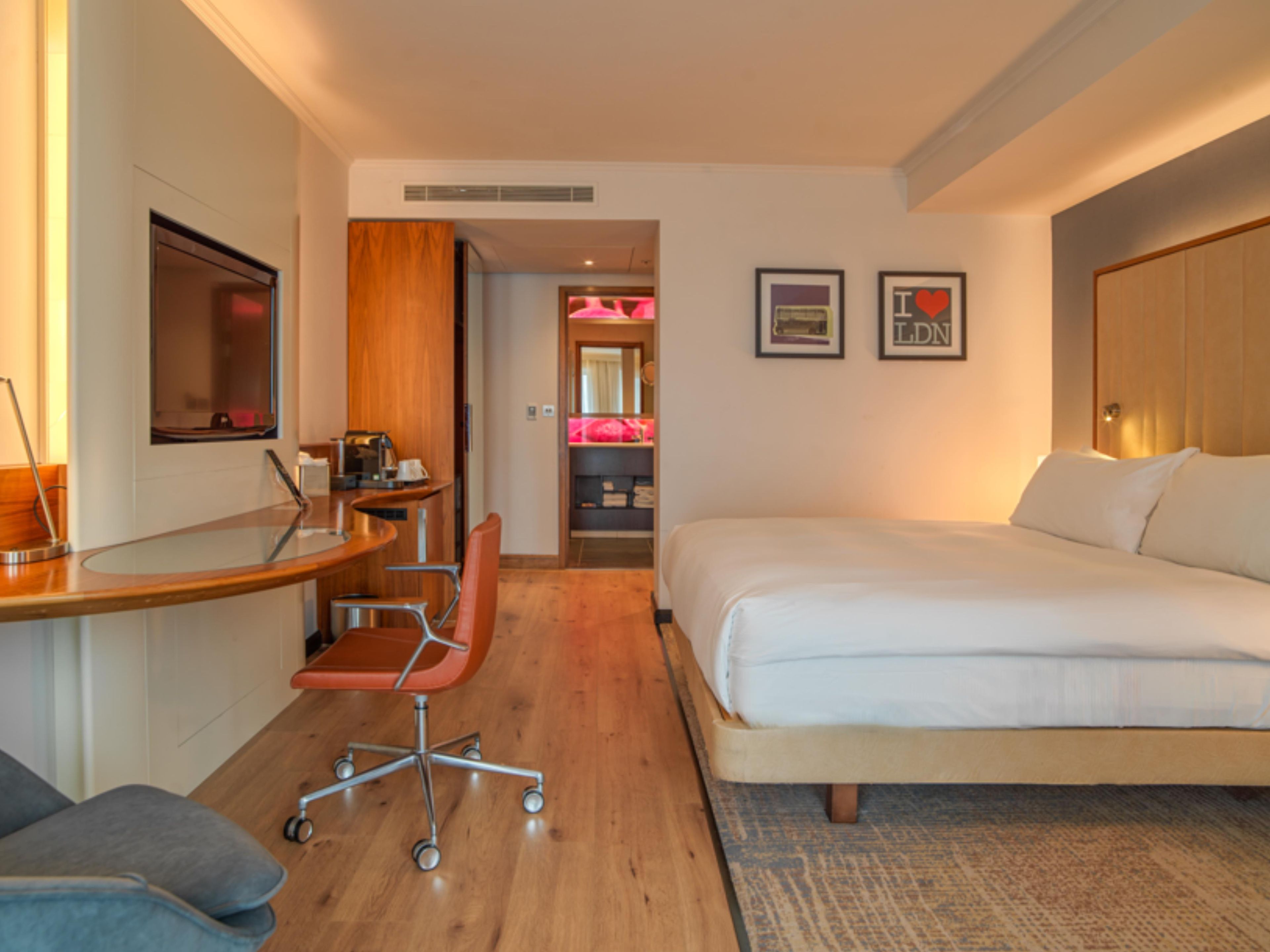 Habitación de hotel con cama, escritorio, silla y una peque ña kitchenette.