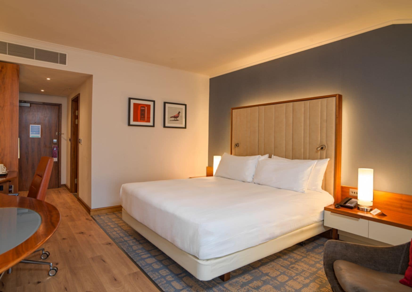 A hotel room with a large bed, a desk, a chair, and a small table.