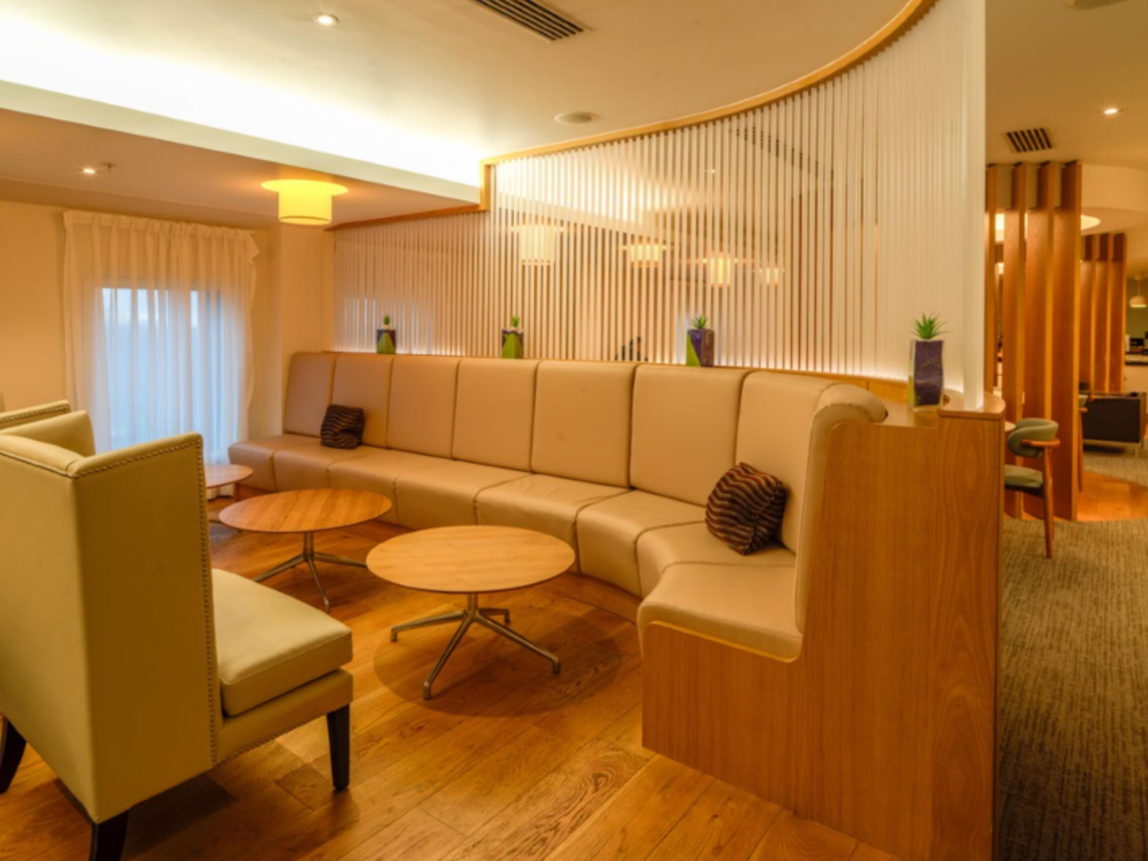 Una sala de estar moderna con un sofá, dos mesas redondas y un mostrador de recepción de madera.