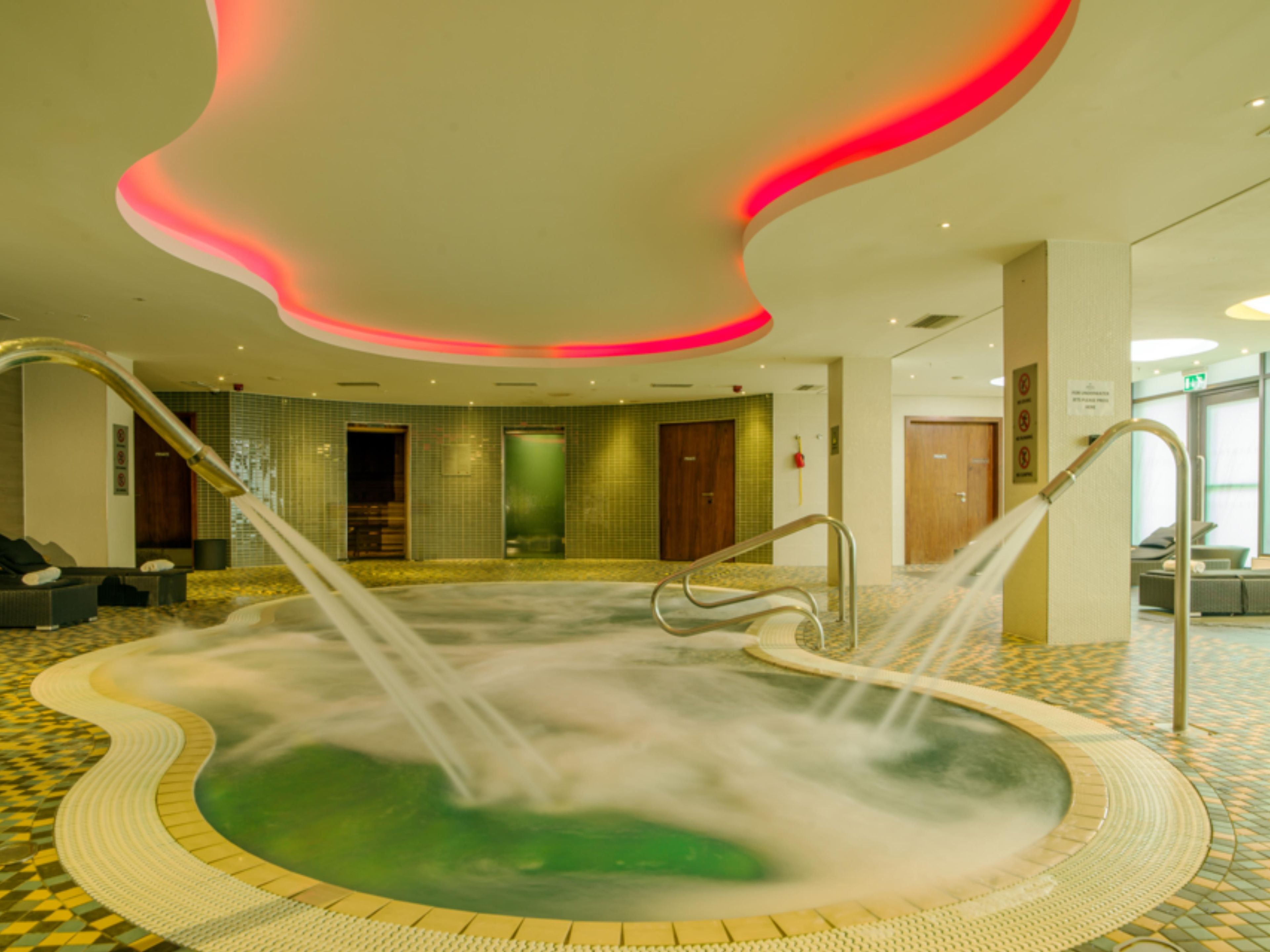 A spa area with a hot tub, seating area, and a tiled floor.