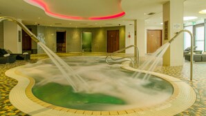Un espacio de spa con un jacuzzi, zona de estar y piso de baldosas.
