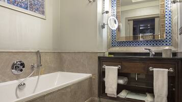 A modern bathroom with a bathtub, a vanity with a mirror, and a towel rack.