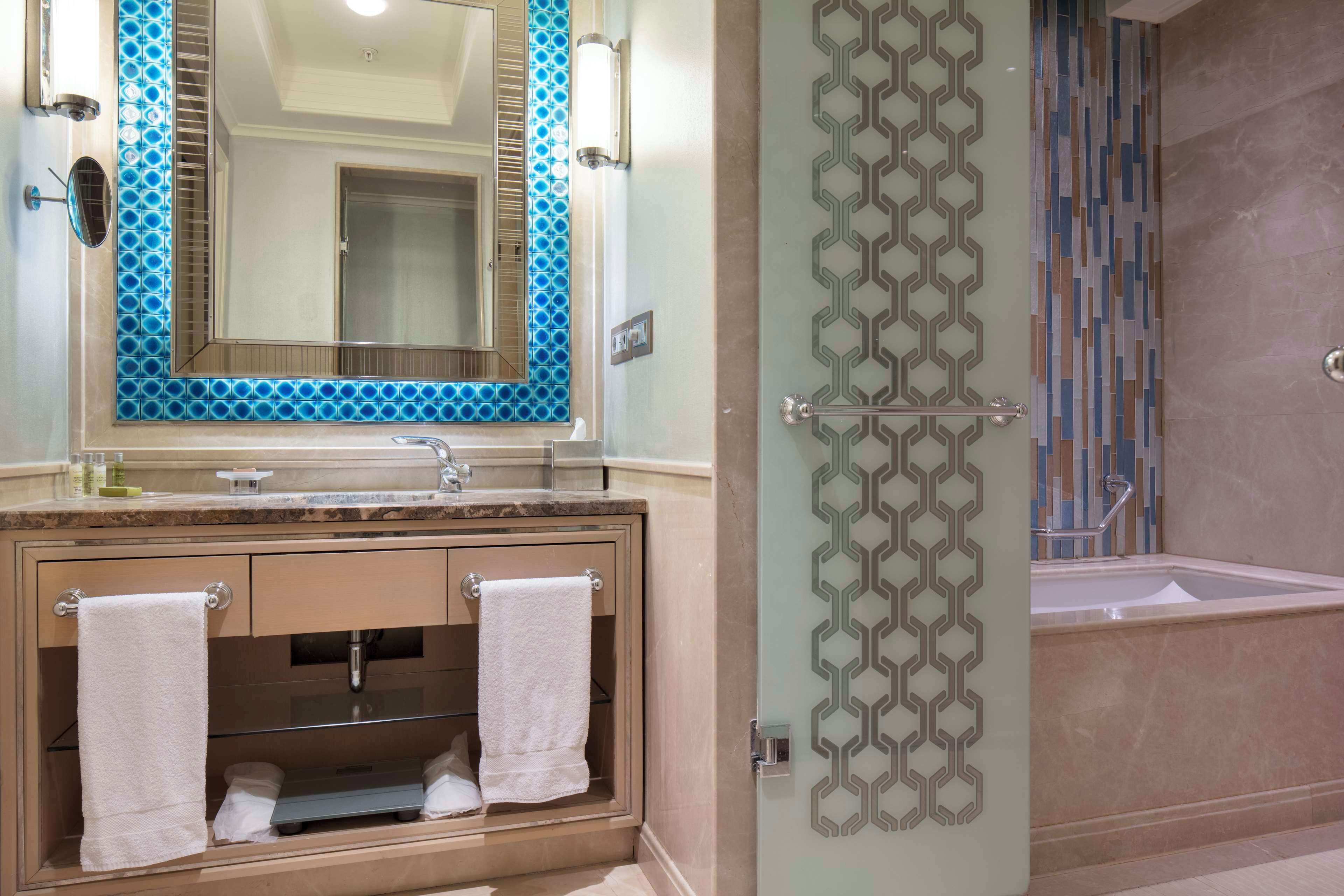 Une salle de bain équipée d’un lavabo, d’un miroir, d’un porte-serviettes et d’un espace douche.