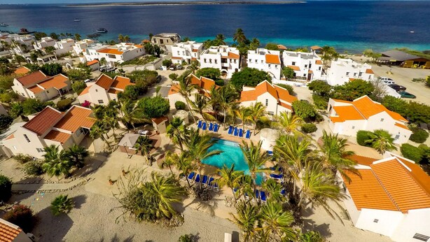 A coastal resort with white buildings, a swimming pool, and a view of the sea.