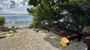 A beach area with a wooden bench, yellow entry markers, and a chain-link fence.