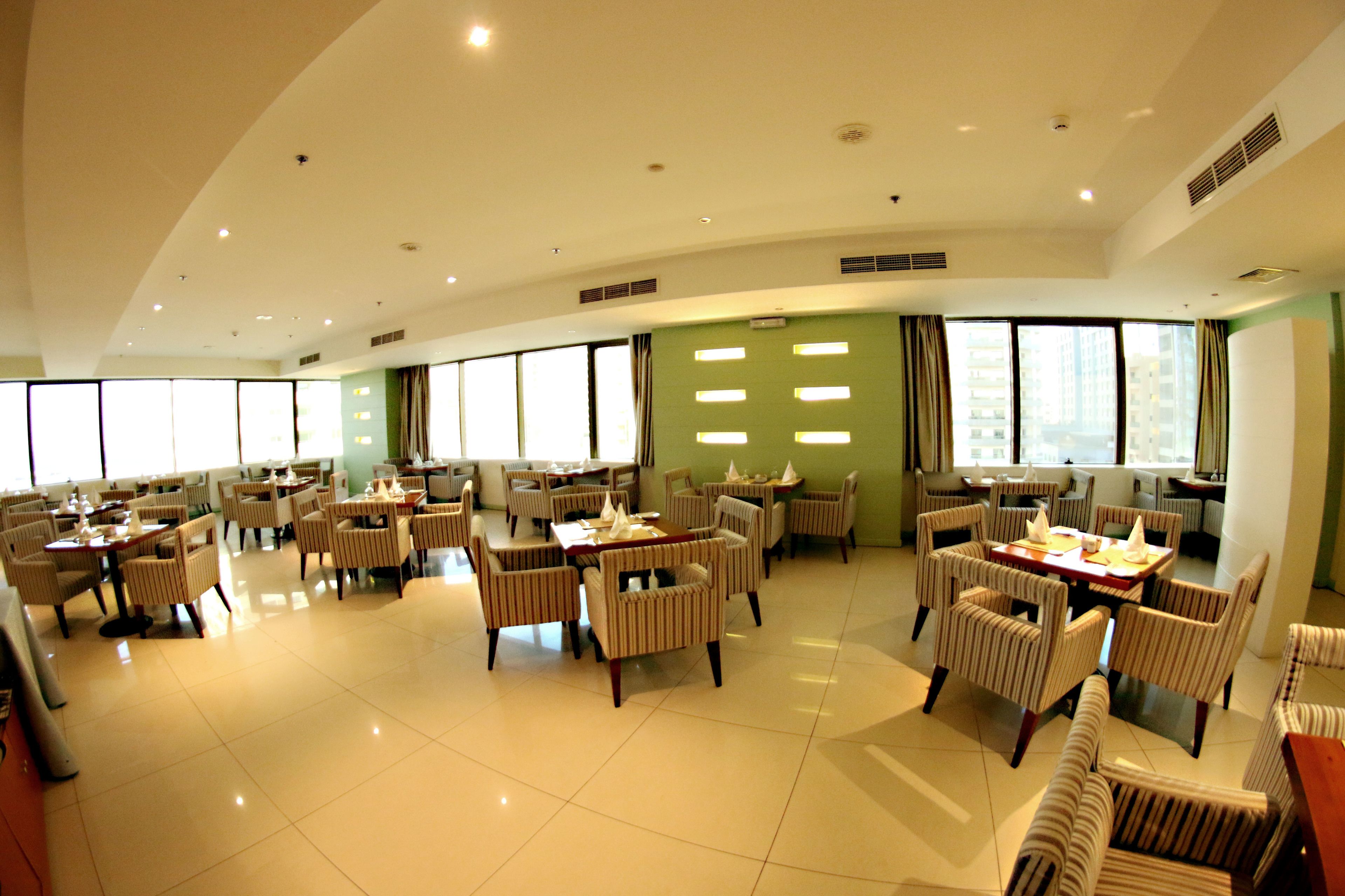 A spacious dining area with multiple tables and chairs, large windows, and a clean, modern design.