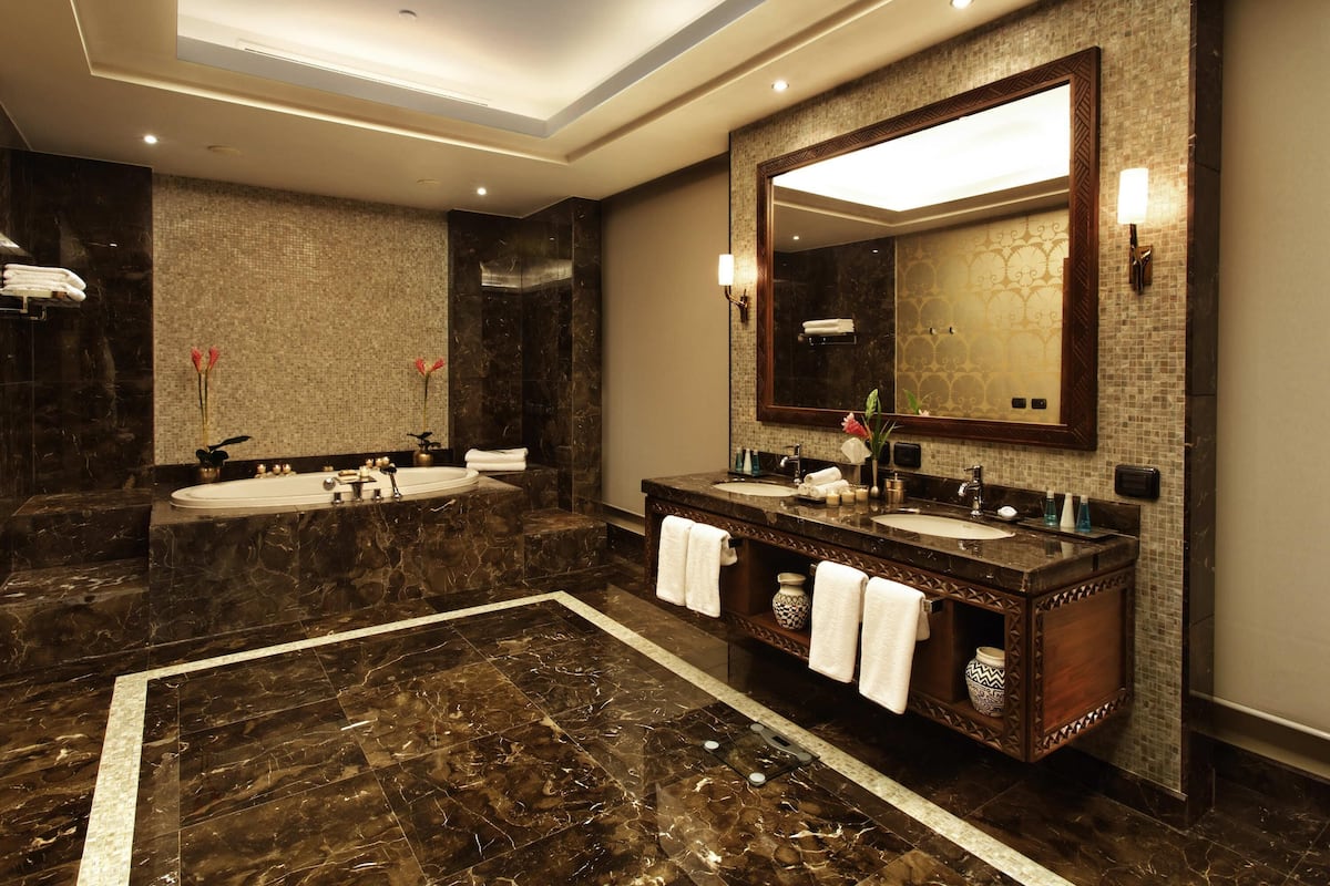 A modern bathroom with two sinks, a large mirror, and a bathtub.