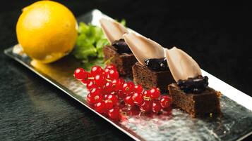 A dessert plate with chocolate pieces, red currants, and a lemon.