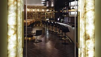 A bar area with a curved counter, multiple bar stools, and a patterned wall in the background.