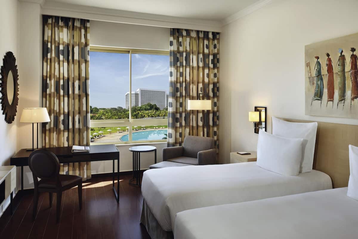 Ein Hotelzimmer mit Bett, Schreibtisch, Stuhl und Blick auf einen Pool und Gebäude.