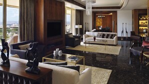 A modern living room with a flat-screen TV, sofas, a coffee table, and a view of the city. - Mövenpick Ambassador Hotel Accra (Accra)