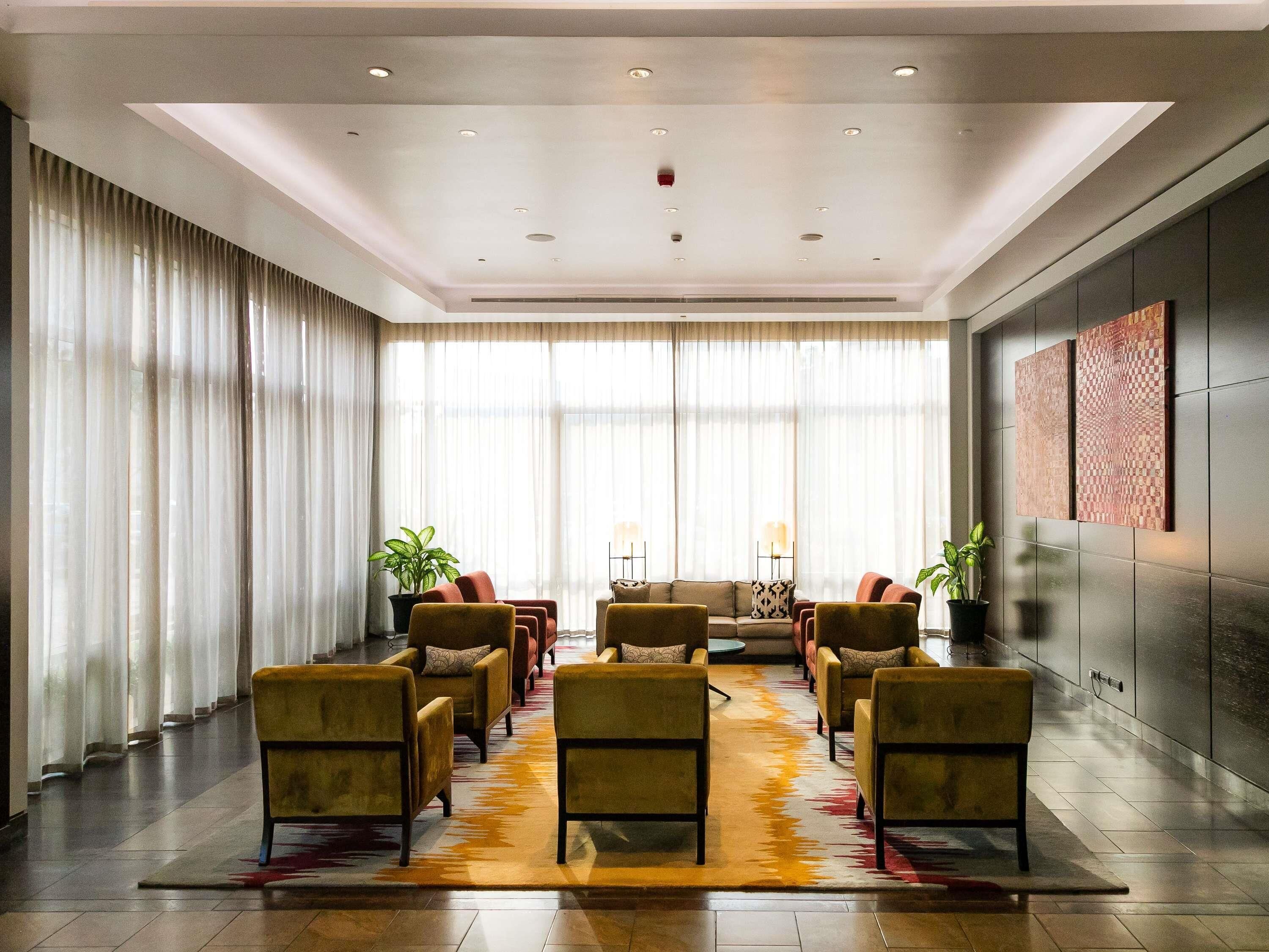 A modern lobby with a seating area, large windows, and a decorative rug.