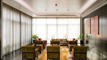 A modern lobby with a seating area, large windows, and a decorative rug.