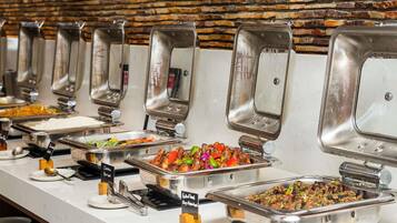A buffet line with various food options, including chicken, rice, and a salad.