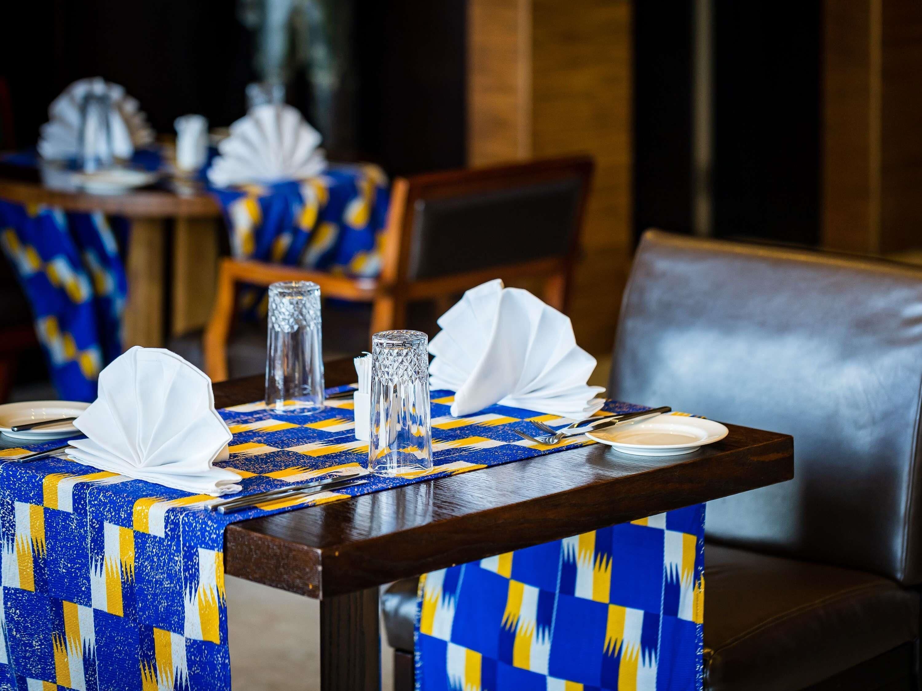 Una mesa de comedor con servilletas blancas, una copa de vidrio transparente, un tenedor y un cuchillo.