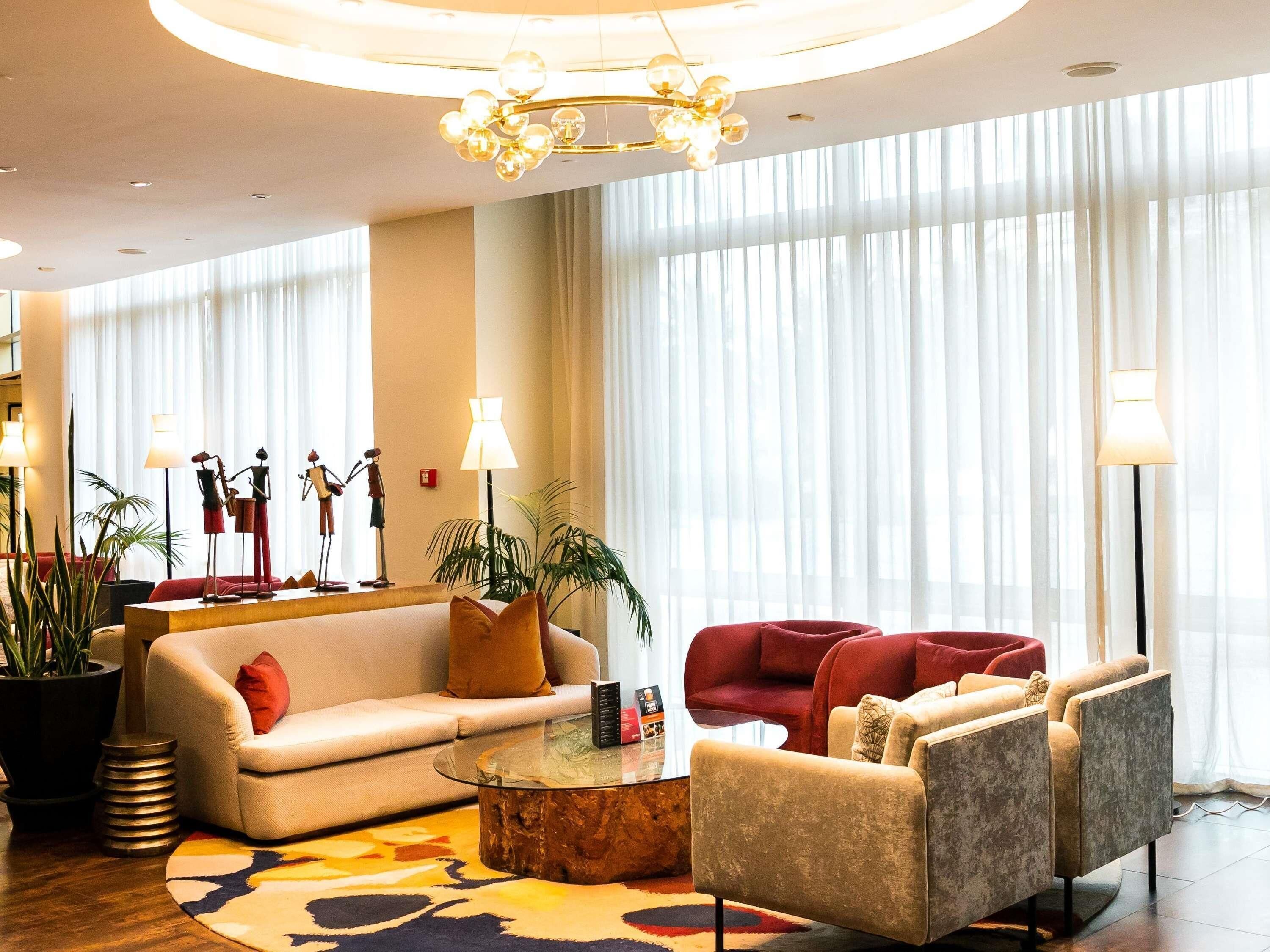 Un moderno vestíbulo de hotel con un sofá, sillones, una mesa de centro y una araña.