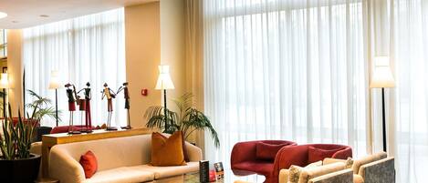 Un moderno vestíbulo de hotel con un sofá, sillones, una mesa de centro y una araña.