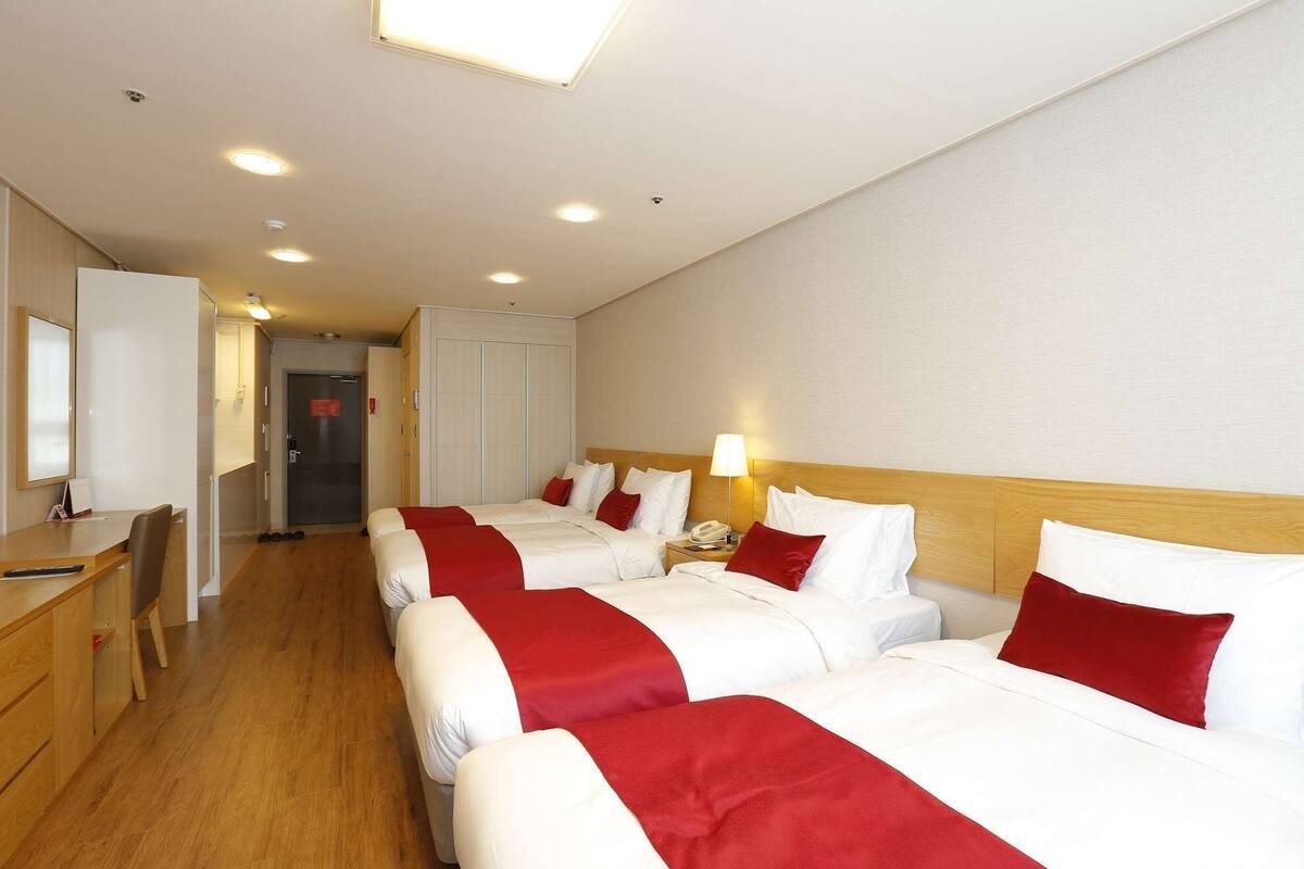 Una habitación de hotel con tres camas, un escritorio y una silla.