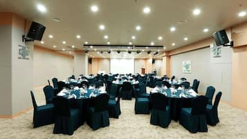 Un salón de conferencias con varias mesas redondas, sillas y piso alfombrado.