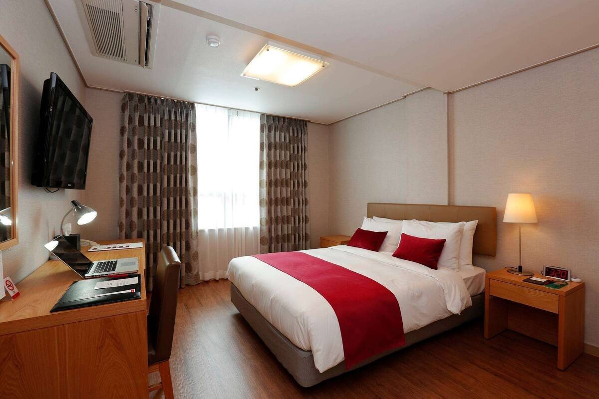 Una habitación de hotel con cama, escritorio y silla.