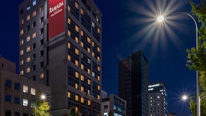 Un immeuble à plusieurs étages, sur lequel on peut voir une grande enseigne rouge avec l’inscription « RAMADA ».
