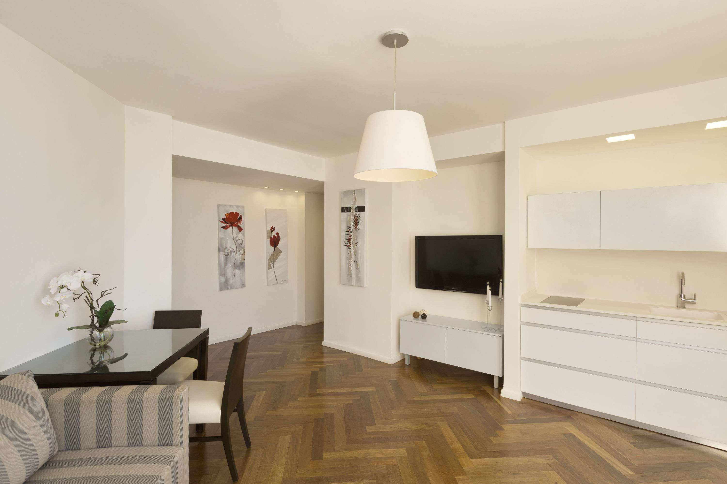 A modern living room with a dining table, sofa, and a TV mounted on the wall.